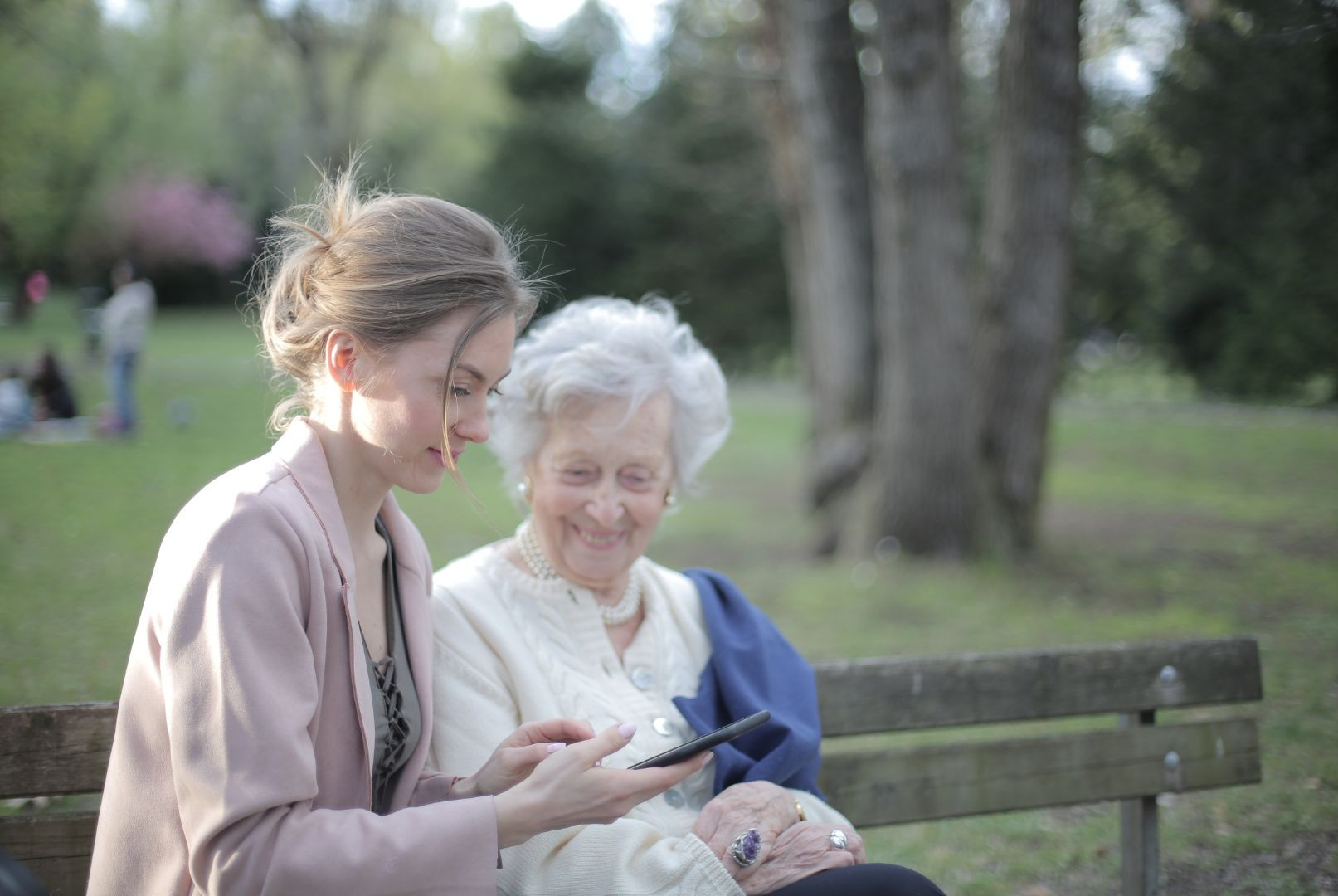 Young woman sitting on a park bench with older woman